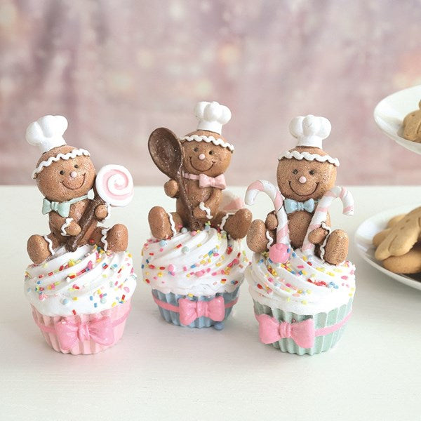 Three cupcakes with gingerbread men decorations on a white surface.