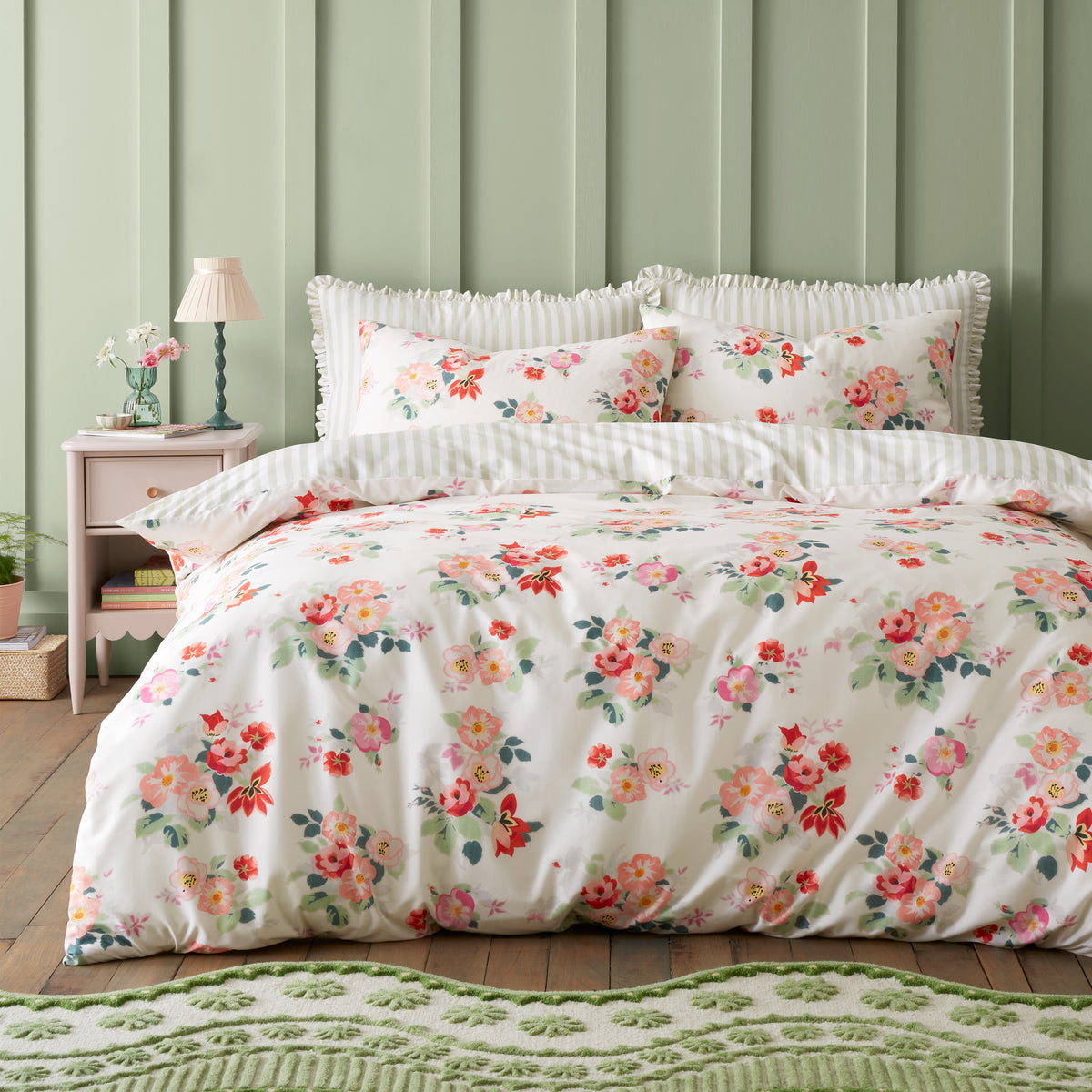Floral bedding set on a bed with a green wall and nightstand in the background