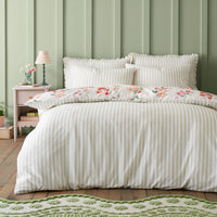 Floral patterned bedding set on a bed with a matching pillowcase, against a green paneled wall.