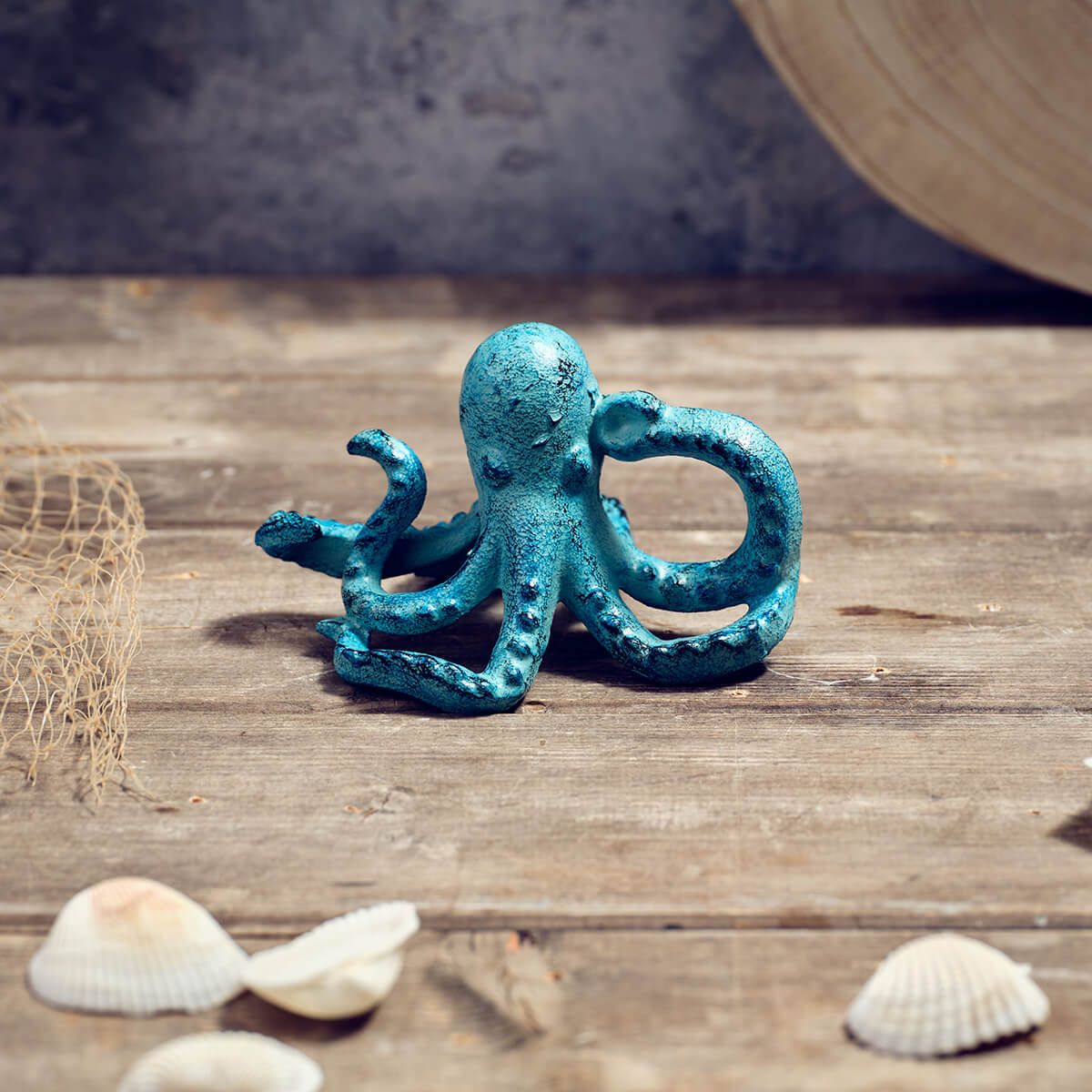 Blue octopus figurine on a wooden surface with shells and a fishing net.