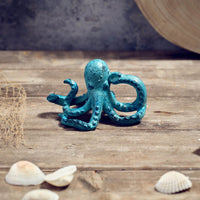 Blue octopus figurine on a wooden surface with shells and a fishing net.