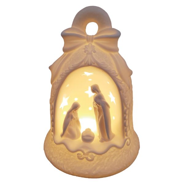 A warm white LED Christmas nativity ornament shaped like a bell with a bow on top, featuring cutout figures of Mary, Joseph, and baby Jesus under star-shaped cutouts, shown illuminated against a white background.